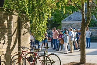 View of people on a guided tour near Cross Campus with foliage and bikes in the foreground.