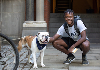 Handsome Dan outside posing with a smiling student who has his arm around the bulldog.